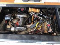 Drawer containing mixed tools including cordless drill, hand tools, clamps, and mallet.