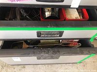 Photo of two closed metal drawers with visible dust and wear, containing soldering tools and supplies inside.