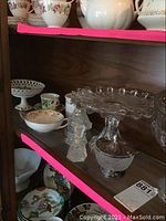 Shelf with hand painted bowls, Hallmark mug, bone china cups, small crystal pieces, and decorative items