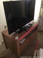 Samsung 42 inch flat screen TV on top of wood TV stand, showing front view and top surface of stand