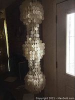 Full view of three-tier capiz shell lamp hanging near door, unlit