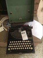 Photo of Remington Portable typewriter inside open green carrying case, showing keyboard and body.