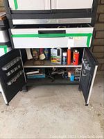 Metal tool storage cabinet with doors open revealing cleaning supplies and tools inside.