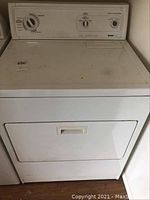 Front view of Kenmore white dryer showing door, handle, and top surface with some marks.