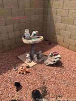 Full view of the bird bath with attached squirrels and surrounding animal statues on gravel ground