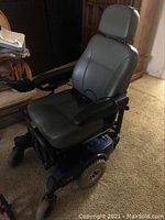 Full view of electric wheelchair showing seat, armrests, base and headrest