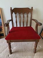 Front view of vintage wooden chair showing red upholstered seat, spindled backrest, and turned legs.