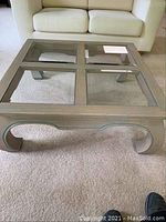 Front angled view of handmade wooden coffee table with four glass top sections and curved legs.
