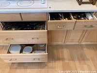 Drawers open showing Lagostina pots and pans, Pyrex dishes, and some clear glass dishes.