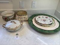 Photo showing assorted vintage ceramic planters, covered Limoges serve bowl, large green serve platter, and smaller decorative plates.