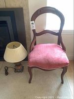 Vintage wood framed side chair next to a table lamp with wood and metal base and beige fabric shade, lighting in room, showing condition and style
