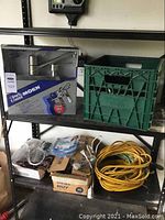 Shelf view showing boxed Moen faucet, green crate with miscellaneous cords, and boxes with coiled extension cords