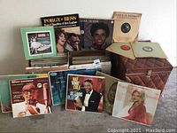 Photo showing multiple classic LP records arranged around a vintage brown diamond quilted naugahyde record case.