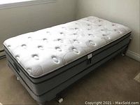 Photo of the Beautyrest Studio single pillow top mattress and box spring on metal frame from an angle.