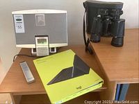Koss KS3370-2 mini hi-fi speaker system with remote control, Logitech keyboard case box with visible damage, Tasco binoculars on wooden surface.
