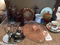 Wide view of all assorted collectible items including various glassware, ceramics, and decorative pieces arranged on a table.