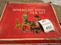 Top view of original red box labeled 'The Little American Maid Tea Set' showing vintage art of children with tea set.