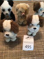 Set of five plush wind up toys, three brown and white dogs, one brown bear, and one panda.