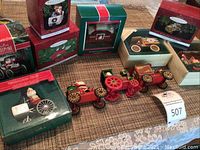 Multiple boxed Hallmark Keepsake Santa ornaments with vintage vehicles and unboxed ornaments on wooden surface