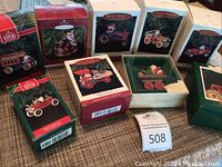 Group of six Hallmark Keepsake Santa with vehicle Christmas ornaments, most in original boxes. One ornament unboxed showing Santa on red fire cart with gifts.