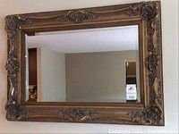 Full view of large rectangular ornate mirror showing carved gold-toned floral frame and beveled mirror edge