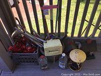 Crate filled with multiple red hummingbird feeders, aluminum poles, a white plastic container, and plastic nectar jugs