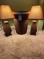 Photo showing the pair of table lamps and the wicker laundry basket together on a carpeted floor against a green wall.
