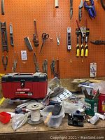 Workbench view showing red Craftsman toolbox, spool of wire, bins of small parts and various loose tools