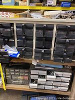 Shelf with multiple small drawers containing fishing and hardware items, including screws and nails.