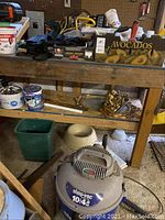 Shop-Vac 10-gallon vacuum beneath wood shelf with assorted items above