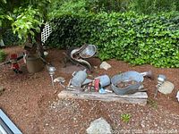 Wide shot showing all metal yard decor items arranged on mulch and some wooden pallets against a hedge background
