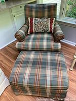 Swivel armchair with plaid upholstery alongside matching rectangular ottoman and decorative pillow on chair seat.