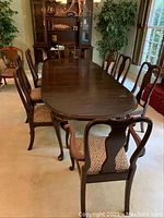 Wide view of six regular dining chairs and two captain's chairs around a wooden dining table in a room.