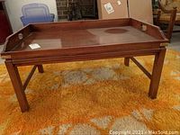 Full view of rectangular wooden coffee table on orange patterned rug.
