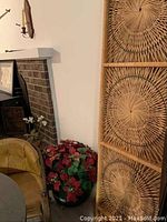 Three-panel wicker screen set up vertically near fireplace, showing height and woven circular design.