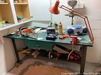 Work bench with assorted chainsaws, circular saw, hedge trimmer, tools, and boombox