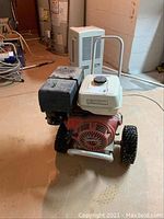 Full view of power washer engine mounted on wheeled metal frame, floor setting.