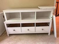 Front view of assembled white sectional storage unit showing three drawers below and three cubbies above, with additional white panels atop.
