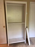 Full view of white wooden bookshelf section with two shelves and visible scratches