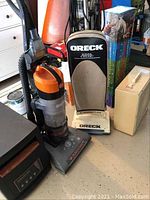 Photo of Oreck HEPA vacuum and Hoover Wind Tunnel vacuum side by side showing both upright vacuum cleaners