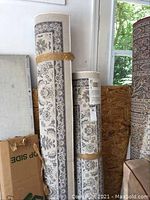 Photo showing two rolled IKEA Valloby rugs leaning against a wall, displaying pattern and neutral color scheme.