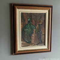 Framed still life oil painting with large green, small clear, and tall bottles, hung on wall.