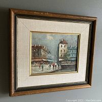 Framed impressionist style oil on canvas painting showing a Paris street scene with pedestrians and buildings, signed by L. Stanio.
