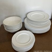 All 30 pieces arranged in four stacks: cereal bowls, dinner plates, luncheon plates, bread plates on wooden surface.