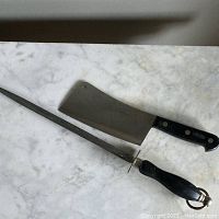 Photo showing the Sabatier cleaver and sharpening steel together on a marble surface.