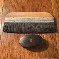 Both brushes laid flat on wood surface showing size contrast and bristle types