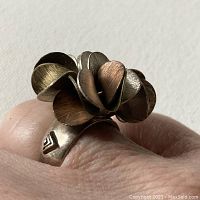 Close-up of articulating silver ring on a finger, showing round disks in silver and copper tones with brushed finish.