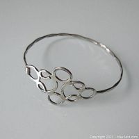 Full view of the delicate silver bracelet showing the linked oval and round wave design