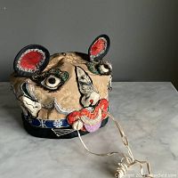 Front view of the antique child's magic hat showing embroidered face and ears.