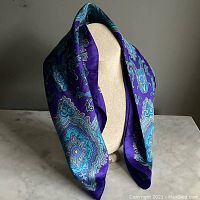 Full display of the purple and blue paisley patterned silk scarf draped on a beige mannequin bust, showing overall colors and design.